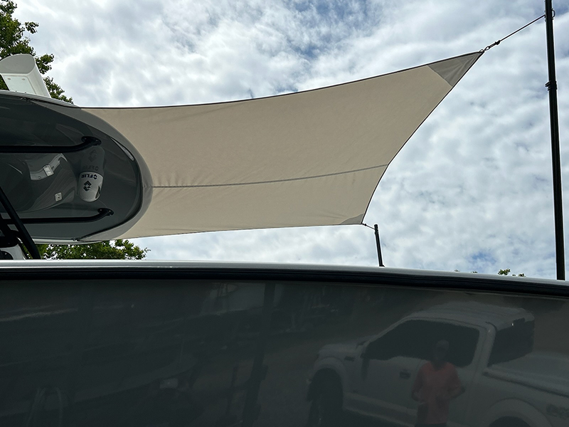 703539495_800px Sunshade sail above vehicles against cloudy sky.